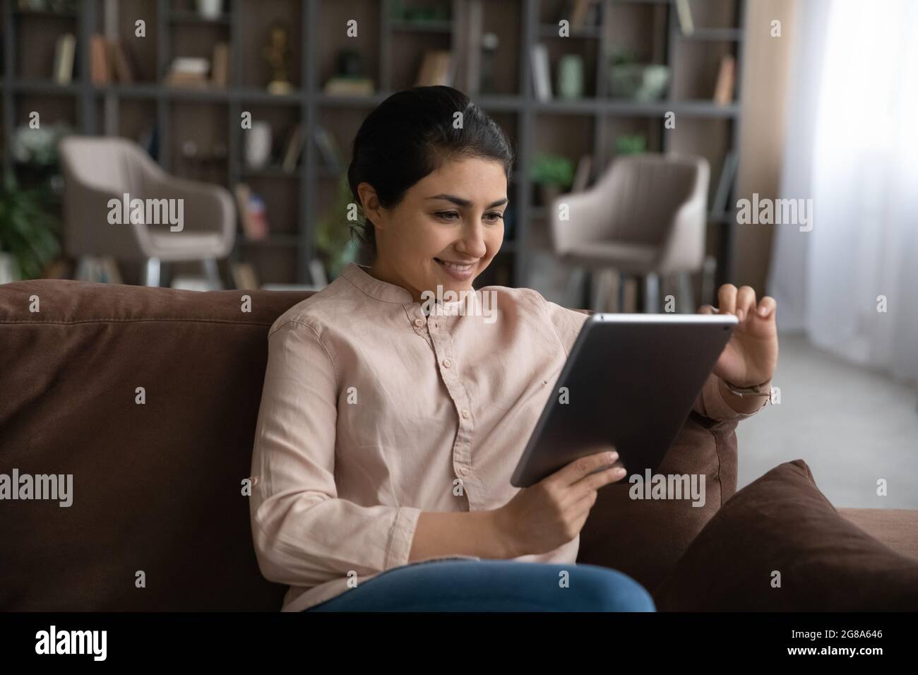 Lächelnde indische Frau verwenden Tablet zu Hause Stockfoto