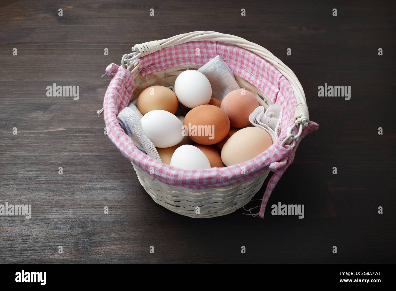 Eier im Korbkorb auf Holztisch. Stockfoto