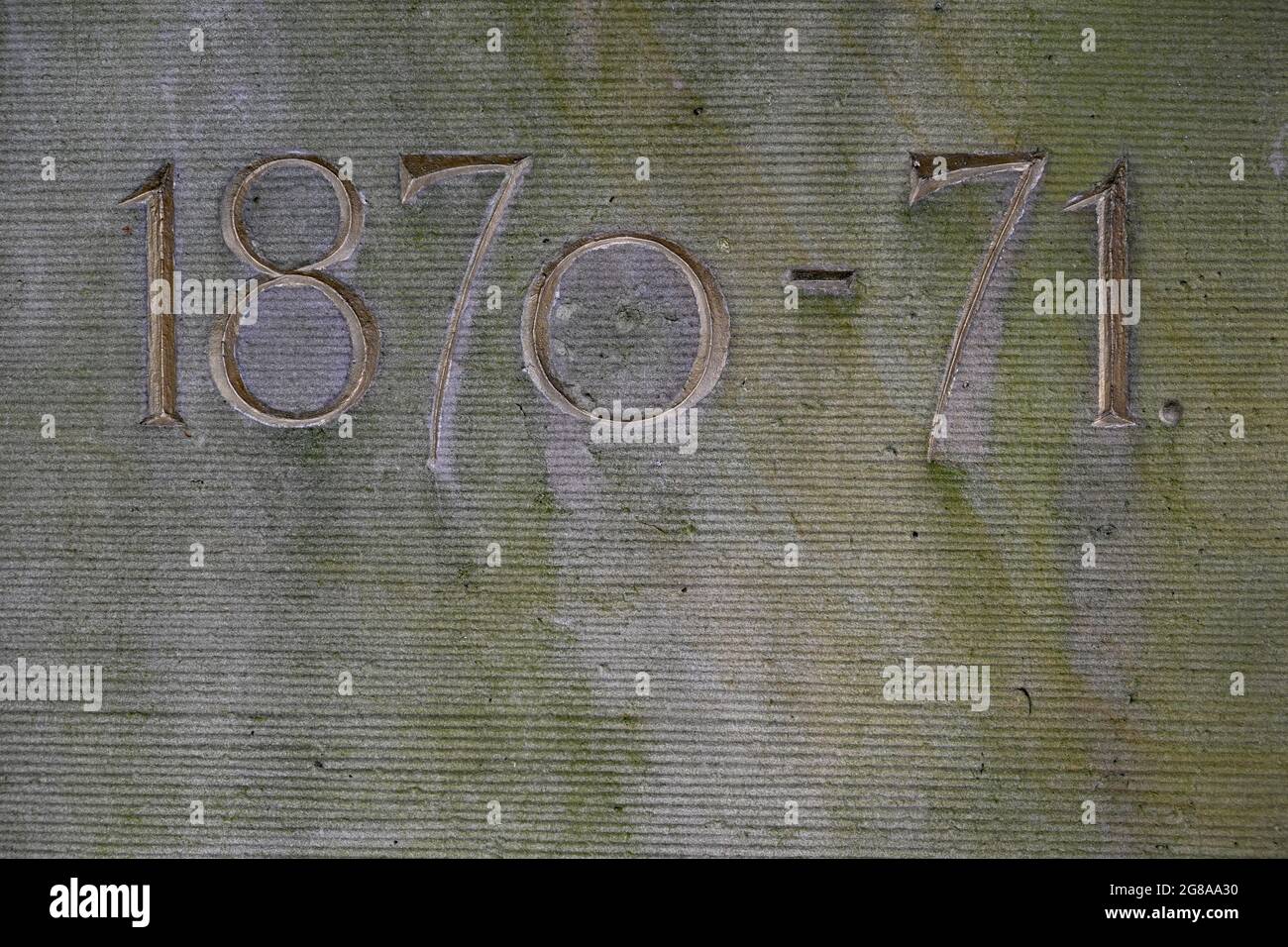 Alter, mit Grünwurzel bedeckter Sandstein mit den Daten des deutsch-französischen Krieges 1870 - 71 Stockfoto