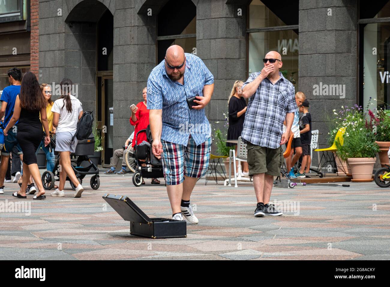 Glatzenkopf, der Münzen auf Keskuskatu in Helsinki, Finnland, in den Koffer eines Straßenmusikers fallen lässt Stockfoto