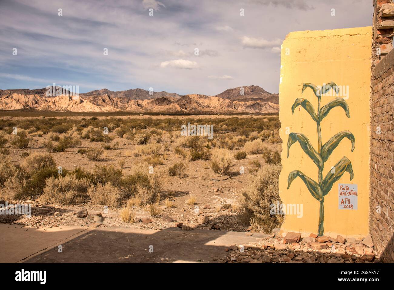 Gemälde einer Maispflanze in einer Wand mit einer desertischen Landschaft im Hintergrund Stockfoto