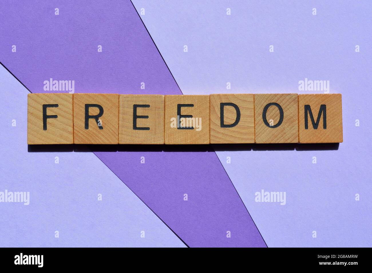 Freiheit, Wort in Holzbuchstaben isoliert auf violettem Hintergrund Stockfoto