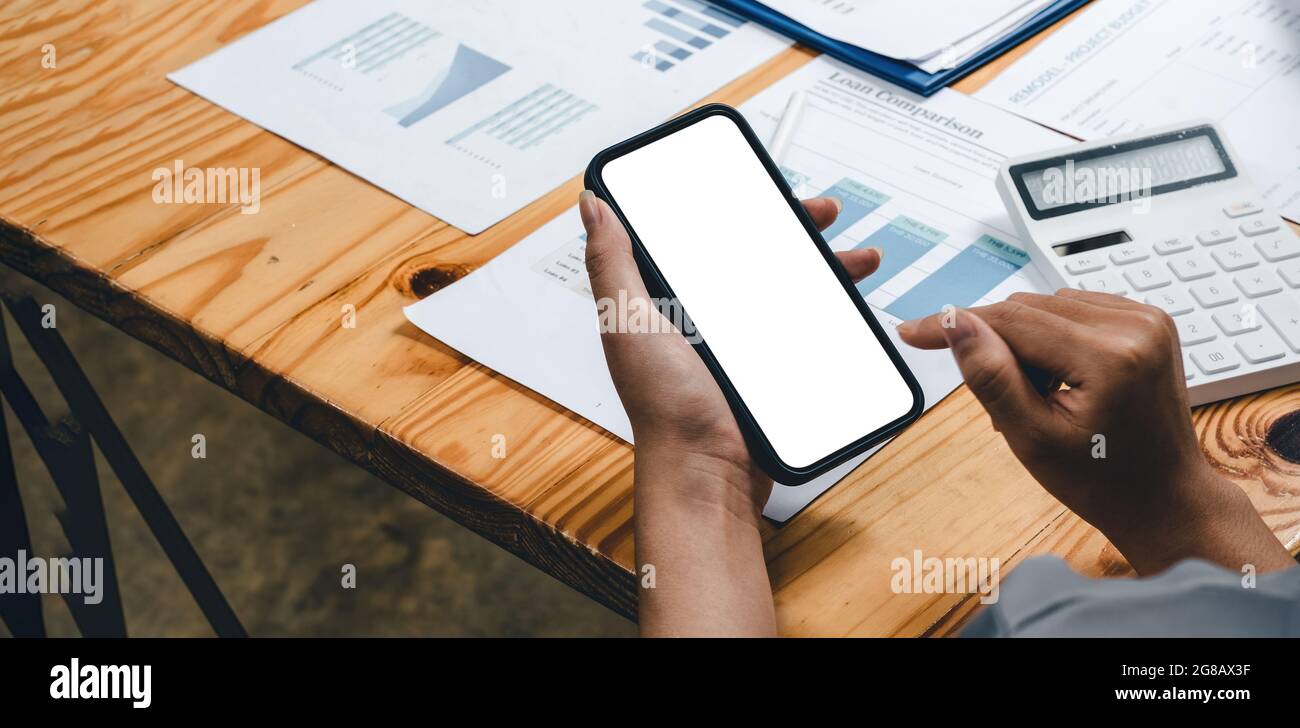 Nahaufnahme einer Geschäftsfrau, die ein Mobiltelefon mit leerem weißen Bildschirm und Hintergrund für die Finanzbuchhaltung eines Unternehmens nutzt Stockfoto