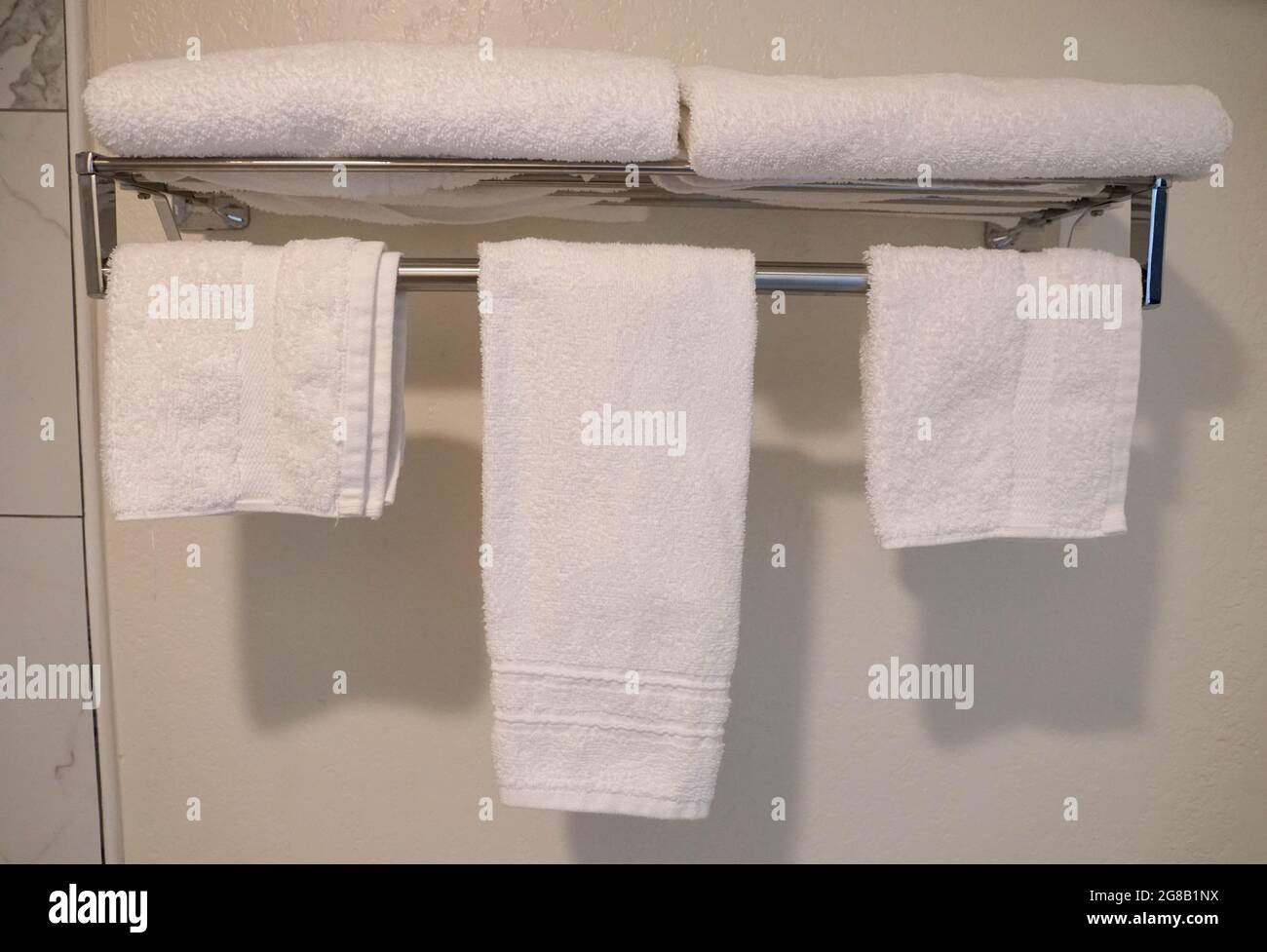Kleine weiße Handtücher hängen an der Badezimmerwand Stockfoto