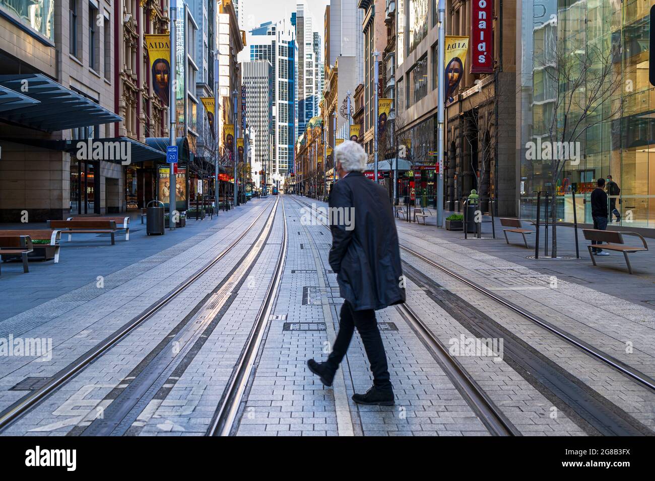 Älterer Mann mit Rücken zur Kamera überquert leere Straßen in Sydney, Australien CBD Stockfoto