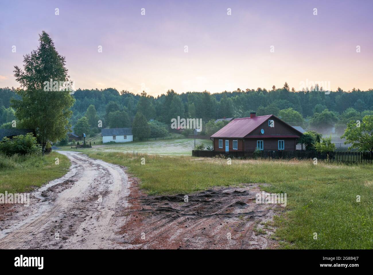 Idyllische Szene des polnischen Dorfes mitten im Wald. Morgennebel über den Feldern. Krasnobród, Roztocze, Polen. Stockfoto