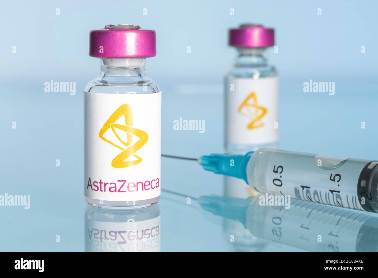 Eine Impfspritze und eine Glasampulle mit einer klaren Flüssigkeit auf blauem Hintergrund mit dem Logo eines Pharmaunternehmens astrazeneca. 15. März 20 Stockfoto