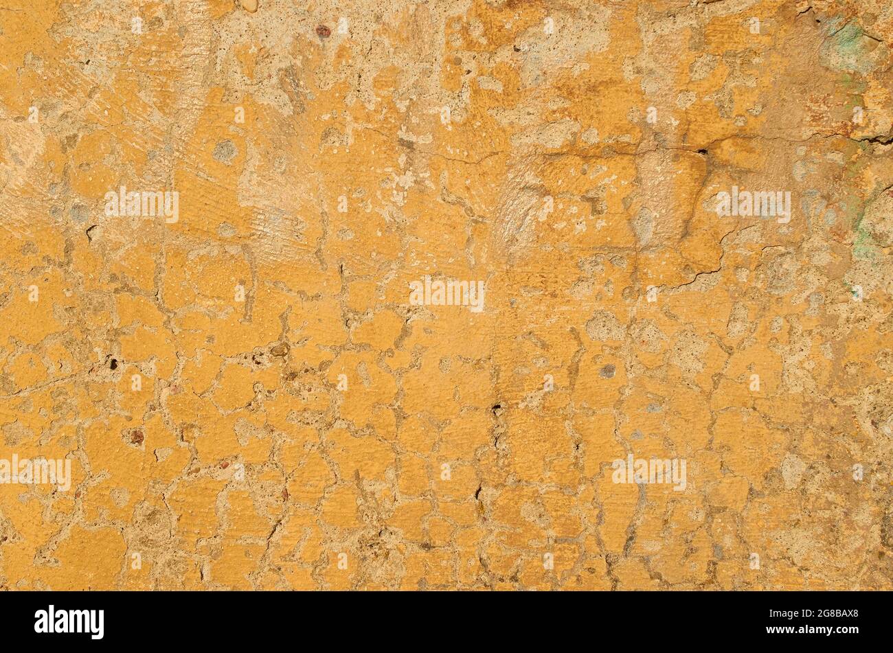 Die Textur der alten rissigen gelben Farbe auf einer Betonwand Stockfoto