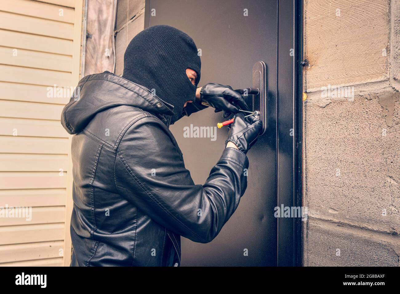 Con man Picking Lock mit schwarzen Lederhandschuhen mit Hilfe spezieller Lock Picks bei Nacht Stockfoto