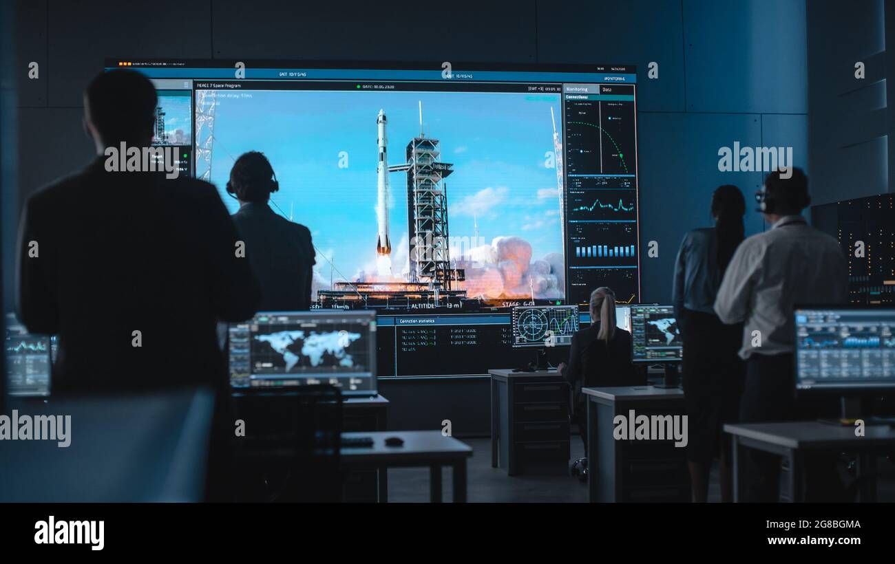 Eine Gruppe von Menschen im Mission Control Center wird Zeuge eines erfolgreichen Raketenstarts. Flight Control-Mitarbeiter sitzen vor Computerdisplays und -Monitoren Stockfoto