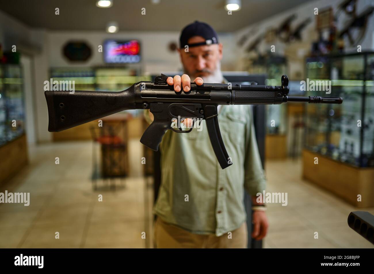 Männlicher Verkäufer zeigt automatisches Gewehr im Waffenladen Stockfoto