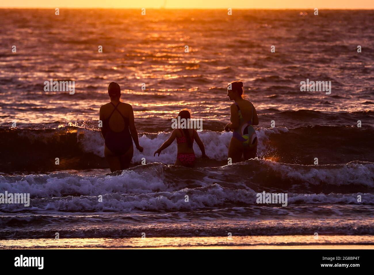 Sonnenaufgang in Helen’s Bay, Co. Down, während die Menschen in der Irischen See schwimmen, um sie am längsten Tag des Jahres an der Sommersonnenwende zu sehen. Stockfoto