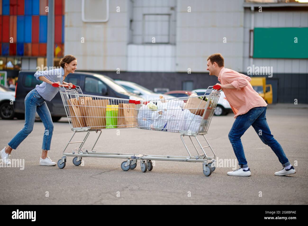 Paar mit Taschen in Karren Witze auf Parkplatz Stockfoto