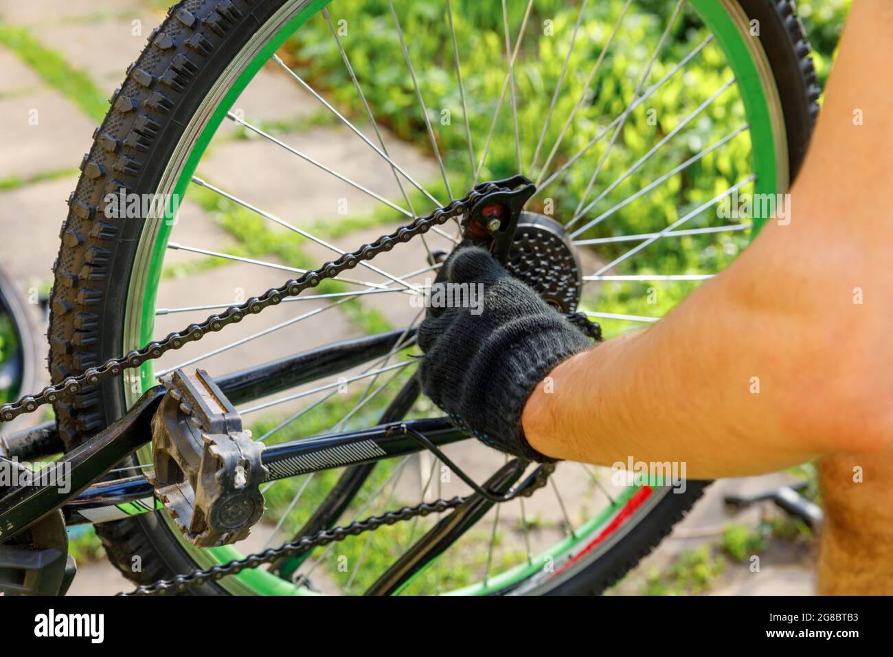 Fahrradmechaniker Mann repariert Fahrrad in Fahrradwerkstatt, im Freien. Die Hand des Fahrradfahrers untersucht, repariert modernes Zyklenübertragungssystem. Fahrrad Stockfoto