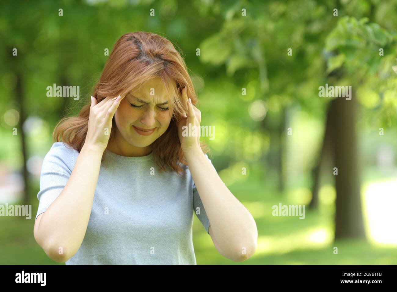 Kranke Frau, die an Migräne leidet und in einem Park läuft Stockfoto