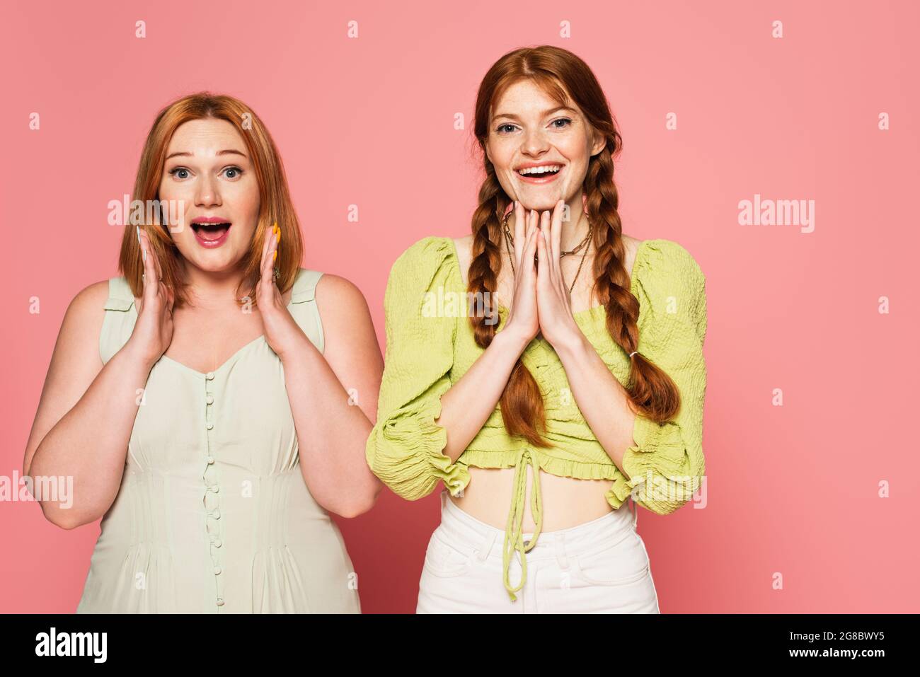 Aufgeregt plus Größe und Sommersprossen Freunde Blick auf Kamera isoliert auf rosa Stockfoto