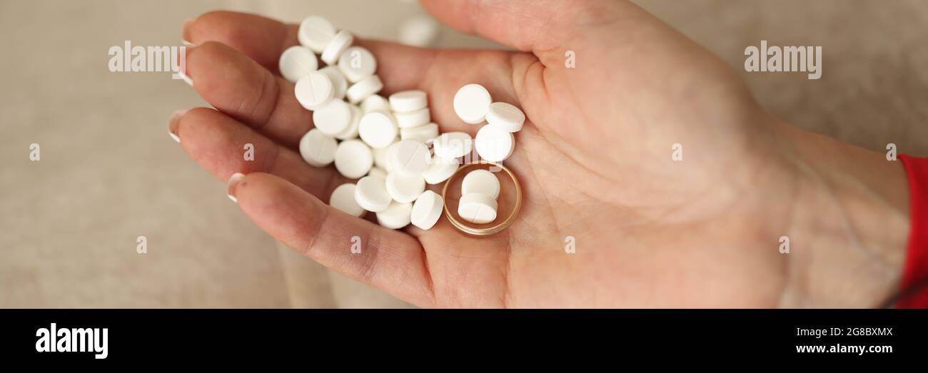 Viele weiße Pillen und Ehering liegen auf Frauen Hand Nahaufnahme. Konzept der männlichen Untreue Stockfoto