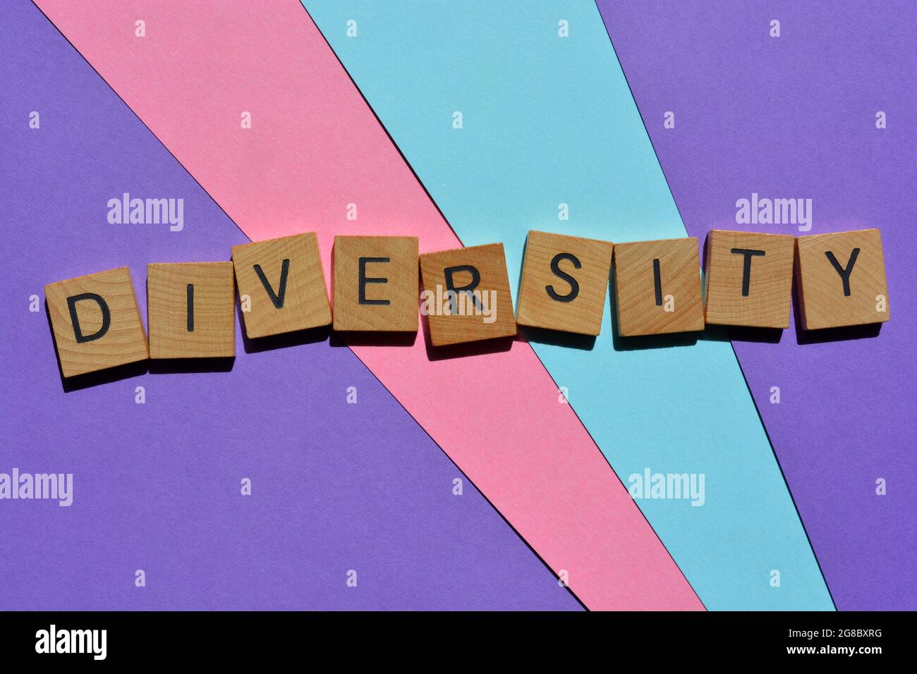 Vielfalt, Wort in Holzalphabet Buchstaben isoliert auf blauem, rosa und lila Hintergrund Stockfoto