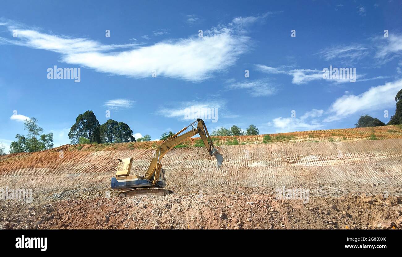 Bagger an einem Hang, beteiligt an Erdbauprojekten oder Straßenarbeiten. Stockfoto