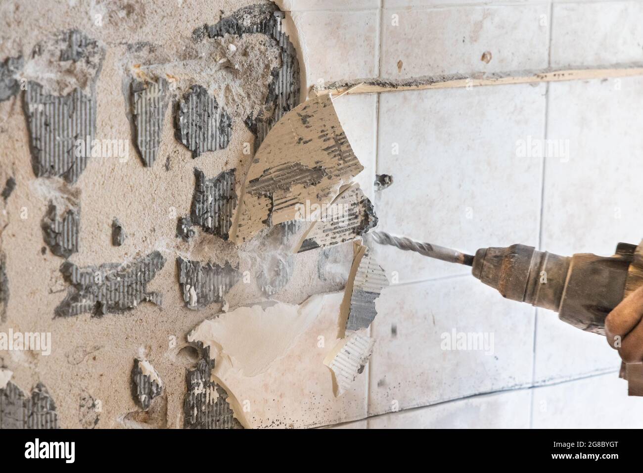 Arbeiter verwenden Abbruchhammer Bohrer, um Fliesen von der Wandoberfläche zu brechen. Bewegungsunschärfe beabsichtigt. Stockfoto