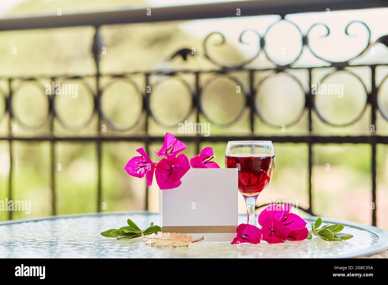 Glas Rotwein, rosa Blumen von Bougainvilleaon Garten Hintergrund. Nachbau einer Postkarte oder Einladung. Speicherplatz kopieren Stockfoto