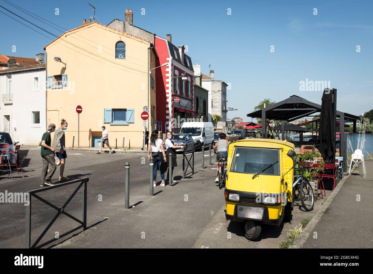 Die Menschen gehen entlang der Straße an der Loire vorbei an bunten Restaurants und Cafés im alten Fischerdorf Trentemoult, Frankreich. Stockfoto