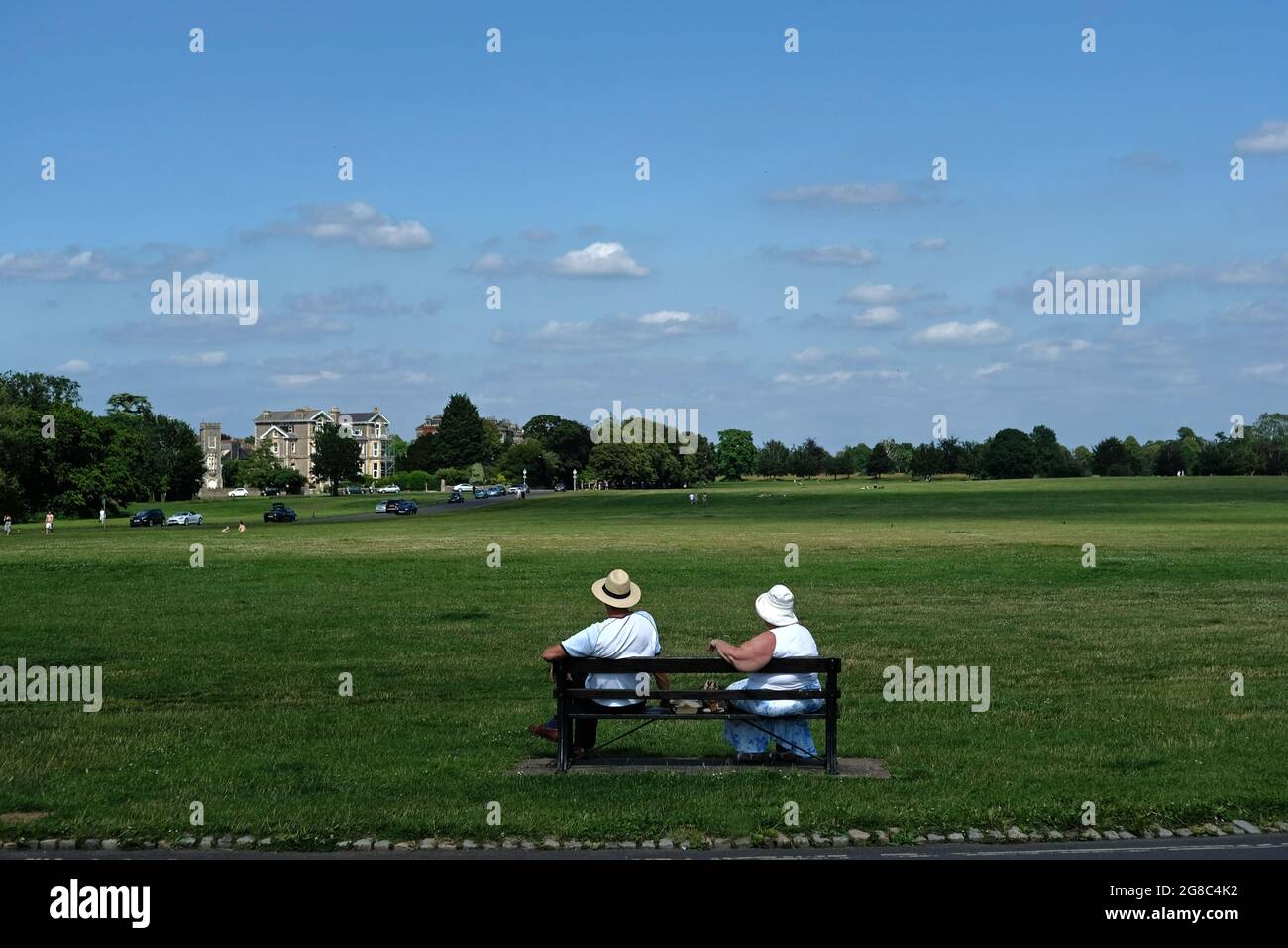 Zwei ältere Menschen sitzen in der Sonne auf Bristol Downs und tragen Sonnenhüte. Stockfoto