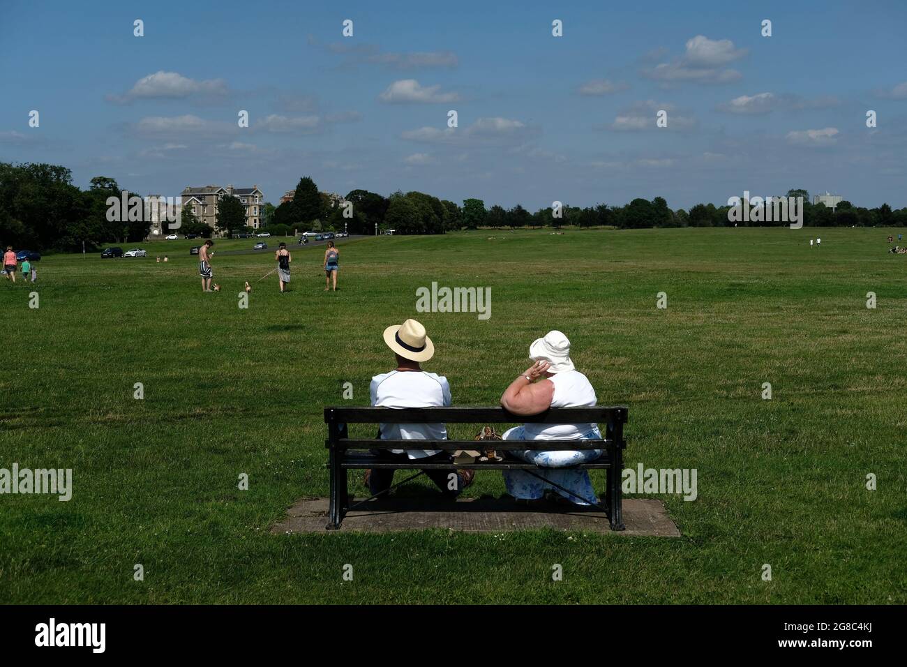 Zwei ältere Menschen sitzen in der Sonne auf Bristol Downs und tragen Sonnenhüte. Stockfoto