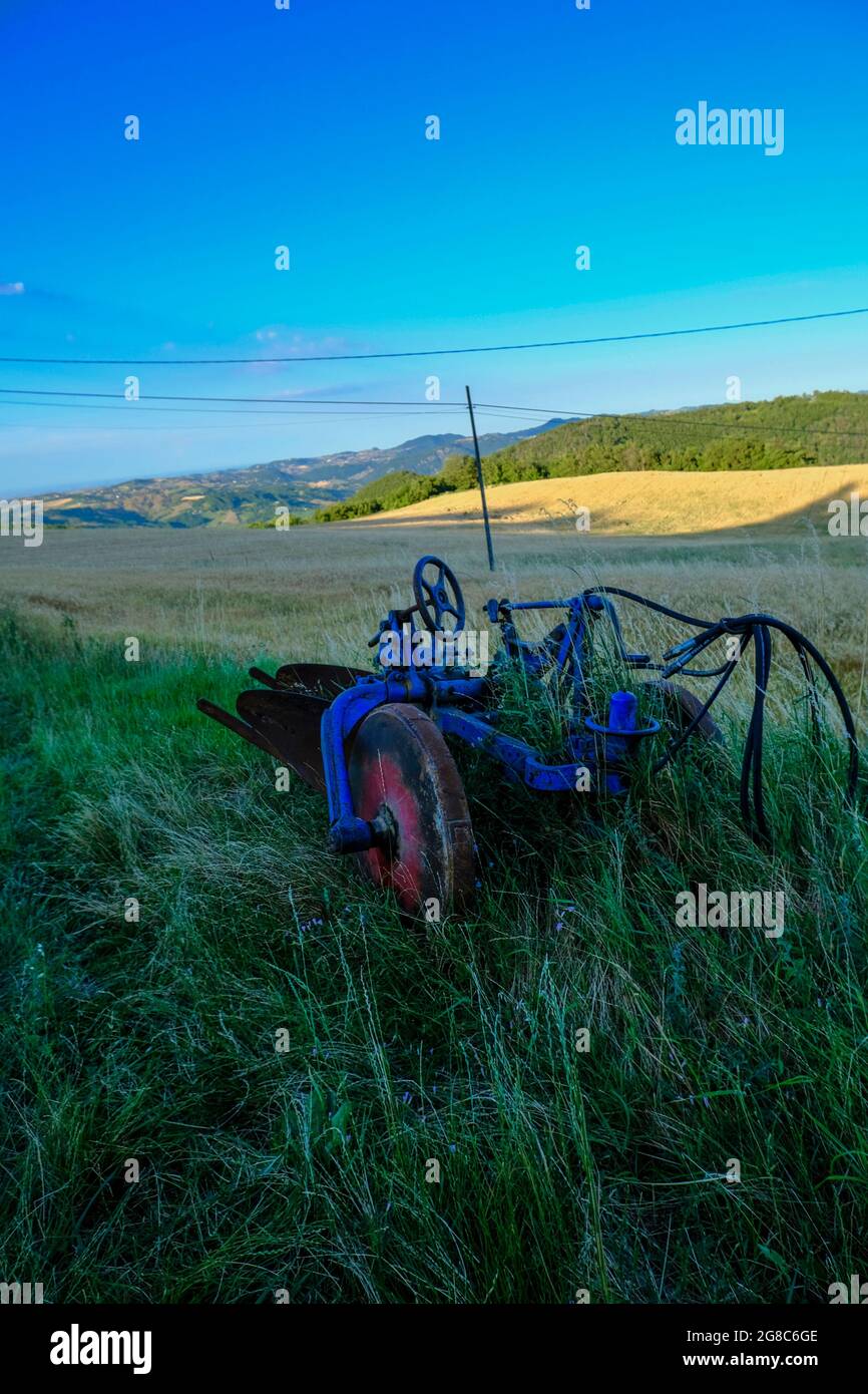 Ein alter blauer Traktor auf dem Feld. Sonnenuntergang über dem landwirtschaftlichen Feld. Vertikal Stockfoto