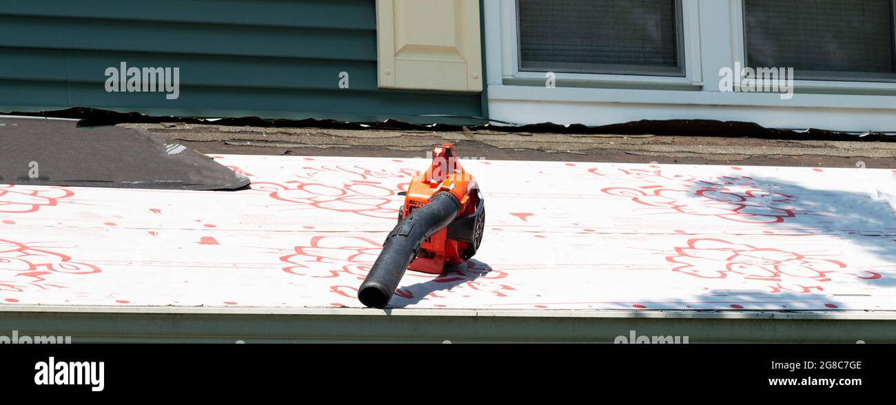 Orange Contractors Laubbläser sitzen auf einem Dach eines Wohnhauses, das ersetzt wird. Stockfoto