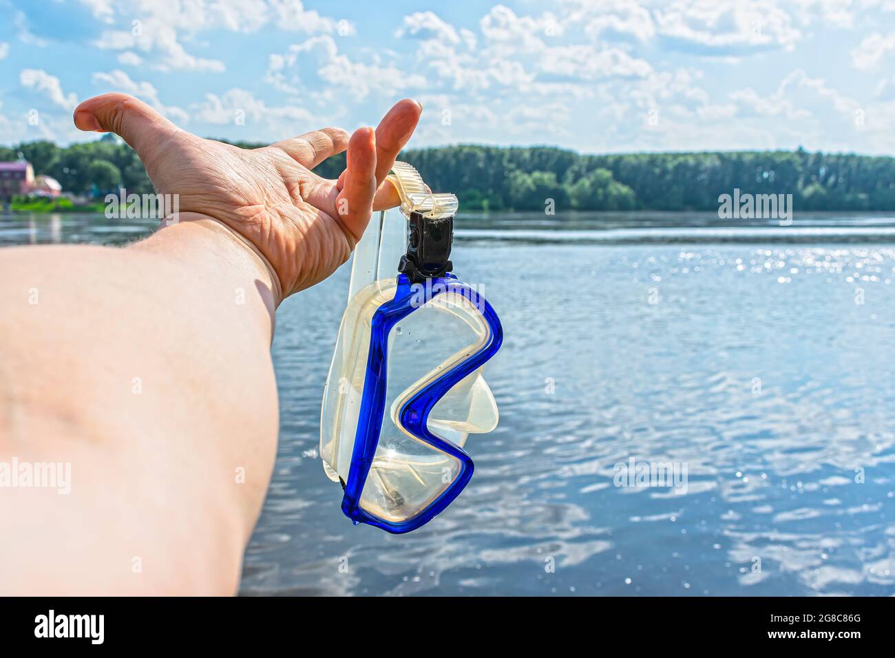 Ein Schwimmer hält an einem warmen, sonnigen Tag eine Schnorchelmaske in den Händen auf dem Flusshintergrund Stockfoto