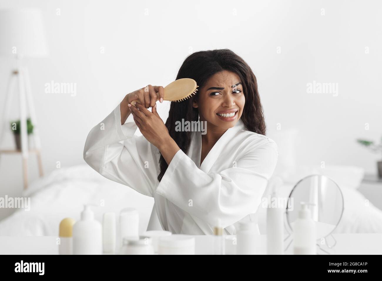 Kosmetik für mattes, trockenes Haar, Behandlung und Home Spa-Therapie. Verärgerte afroamerikanische Frau kann lockiges Haar nicht kämmen Stockfoto