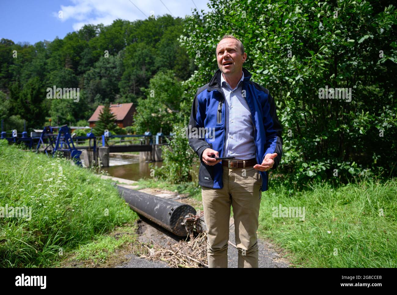 Porschdorf, Deutschland. Juli 2021. Wolfram Günther (Bündnis90/die Grünen), Sachsens Umweltminister, spricht vor einem Wehr auf dem Lachsbach in der Sächsischen Schweiz über die vorläufige Schadensbewertung der Überschwemmungen in Sachsen am Wochenende. Quelle: Robert Michael/dpa-Zentralbild/dpa/Alamy Live News Stockfoto