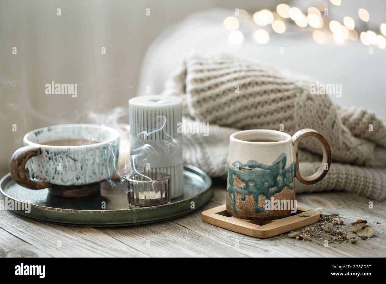 Gemütliche Komposition mit Keramikschalen und Kerzen auf einem unscharfen Hintergrund mit Bokeh. Stockfoto