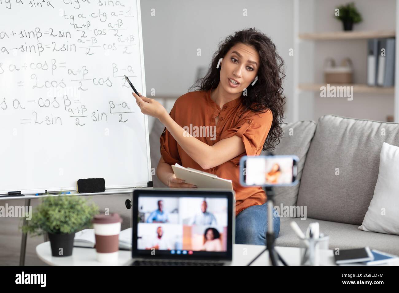 Weibliche Lehrerin in Ohrhörern erklärt den Schülern online trigonometrische Funktionen Stockfoto