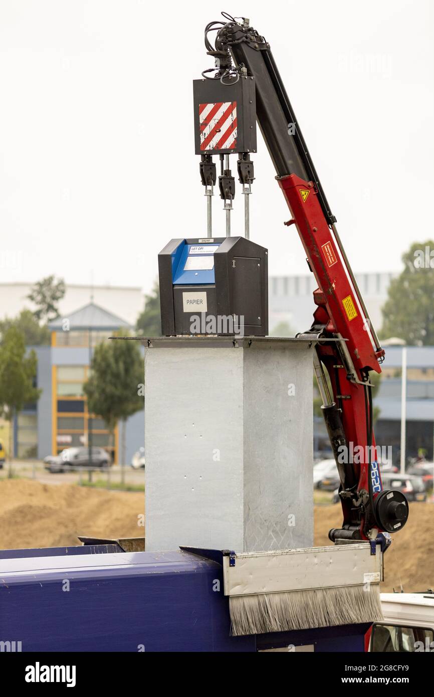 ZUTPHEN, NIEDERLANDE - 14. Jul 2021: Holländischer Müllsammelwagen mit mechanischem Arm, der per Fernzugriff Kartonpapiermüll in einen Lastwagen ablässt Stockfoto