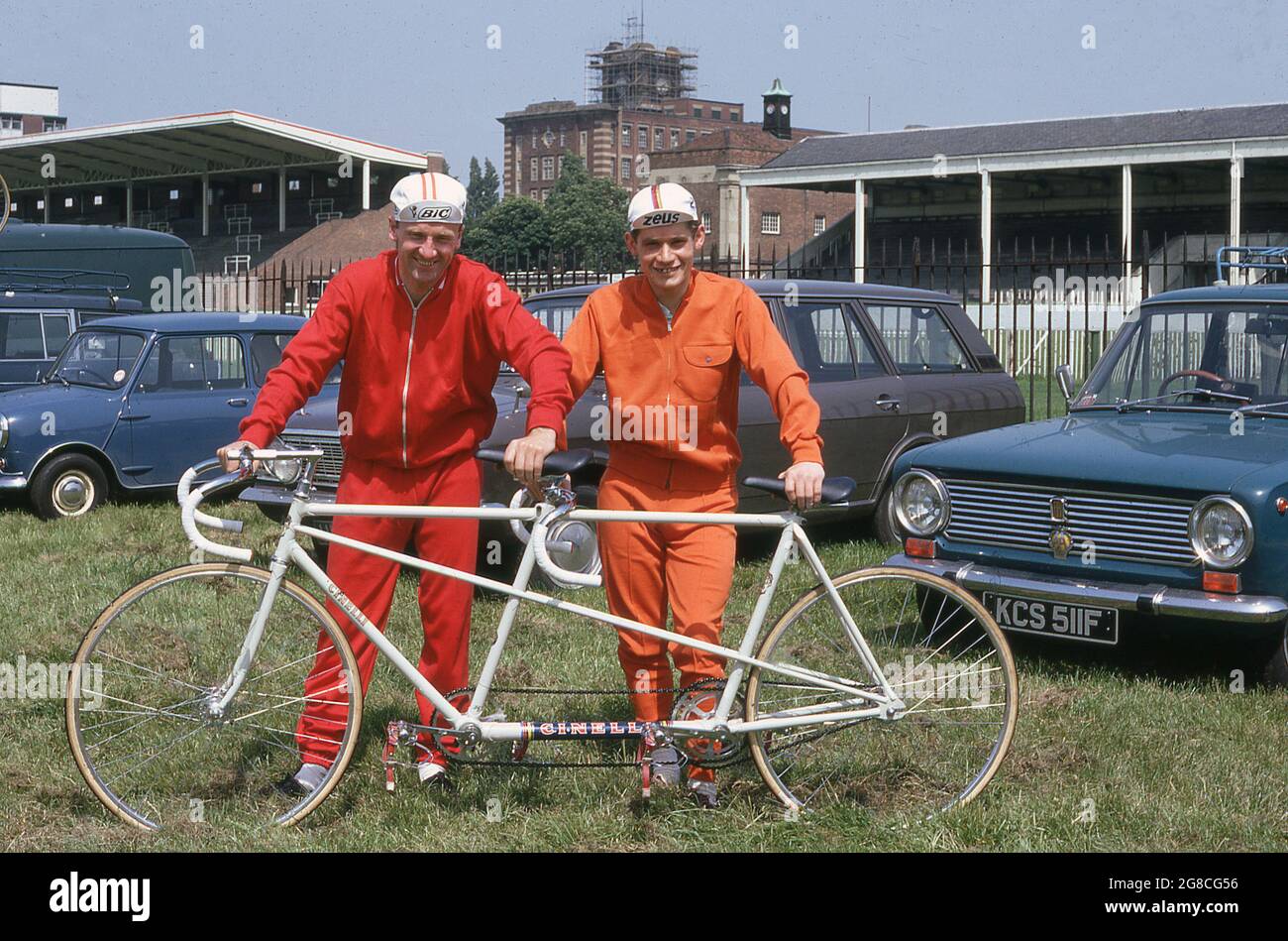 1969, historisch, zwei männliche Radfahrer in ihrer Radfahrausrüstung der Ära, zweiteilige Baumwoll-Track-Anzüge, die draußen für ein Foto mit ihrem Tandem-Festrad-Track-Fahrrad standen, CTC Rally, York, England, Großbritannien. Der Stylistin all White Bike, hergestellt von der berühmten italienischen Firma Cinelli aus Mailand, wurde von Ron Kitching, einer einflussreichen Persönlichkeit im Fahrradhandel in dieser Zeit, mit seinem Geschäft und seinem Katalog von Fahrradprodukten, „Everything Cycling“, nach Großbritannien importiert. Stockfoto