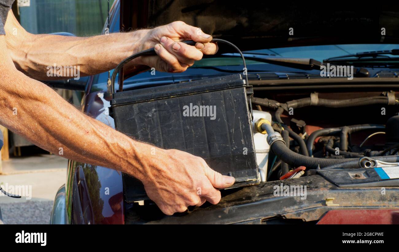 Eine Person ergreift eine Batterie, die in ein Fahrzeug eingebaut werden soll Stockfoto