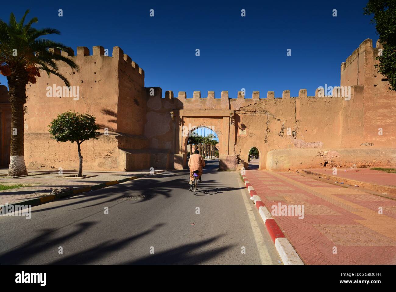 Mann, der mit dem Fahrrad vor der Stadtmauer in Taroudannt Marokko fährt Stockfoto