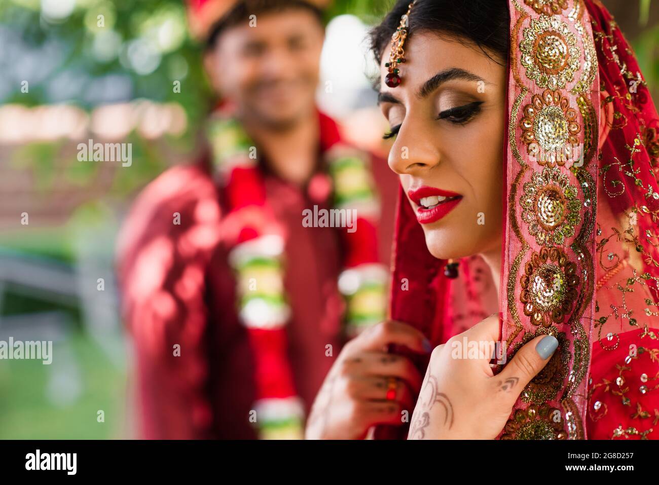 Indische Braut in Sari und Kopftuch in der Nähe verschwommener Mann in  Turban auf dem Hintergrund Stockfotografie - Alamy