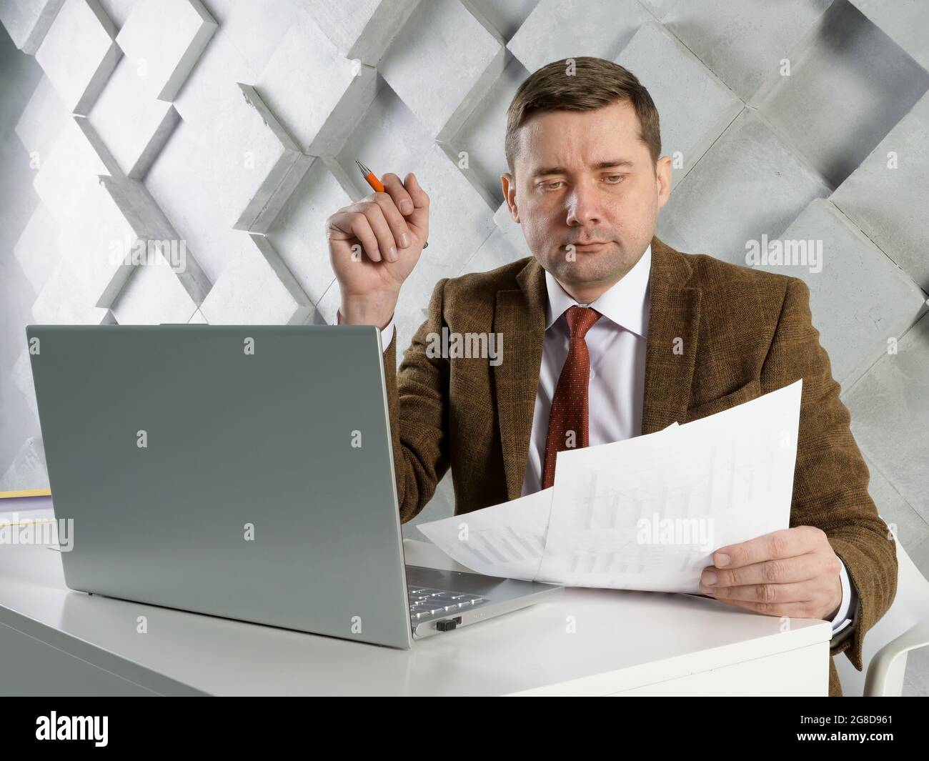 Ein Geschäftsmann mit Computer arbeitet am Arbeitsplatz mit Finanzpapieren. Stockfoto