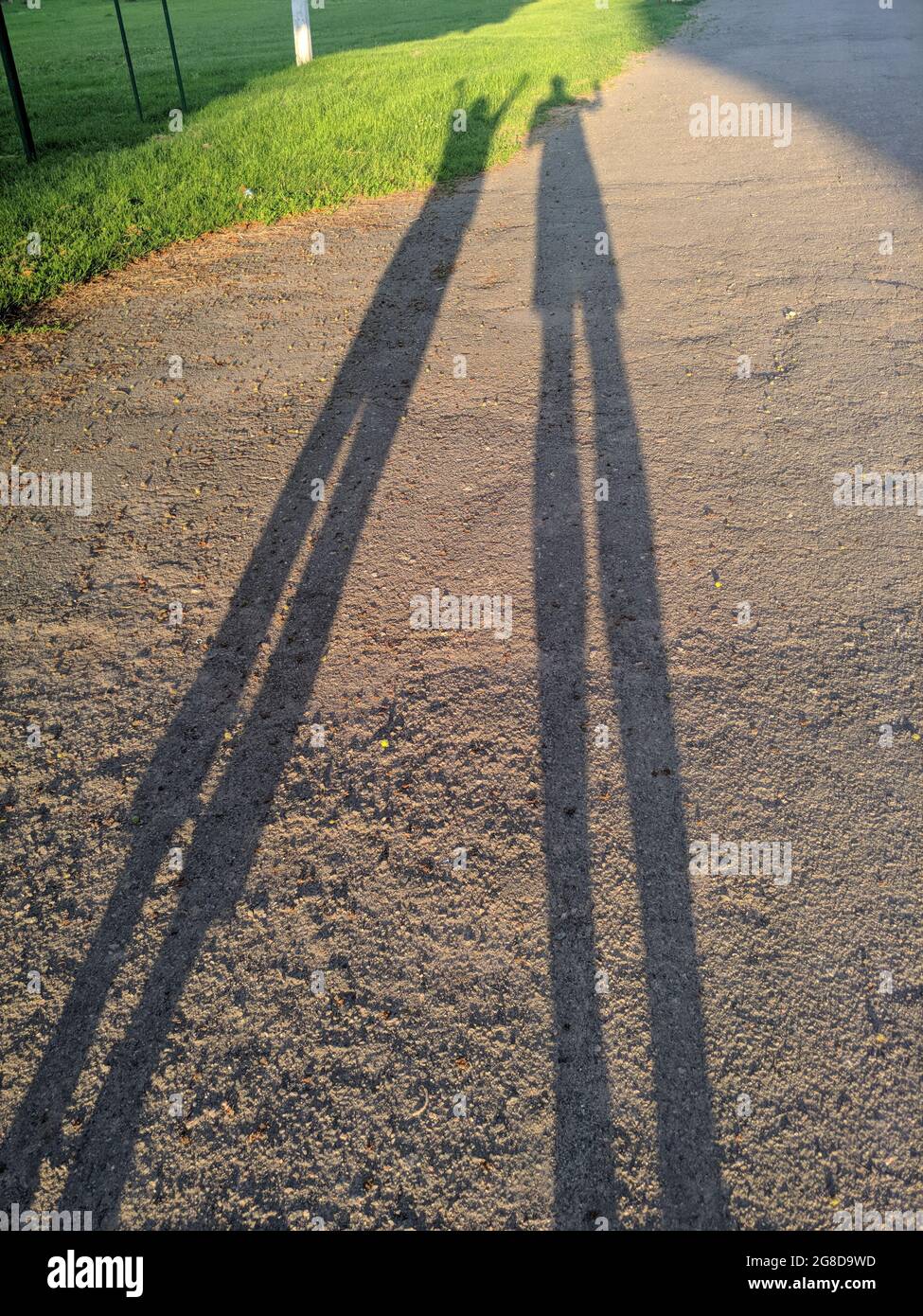 Abstrakte sehr lange Schatten Silhouetten von zwei Menschen auf dem Boden. Sommer weite Aufnahme Stockfoto
