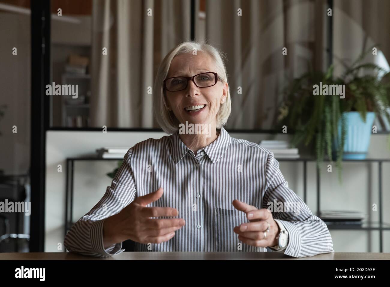 Glückliche reife Lehrerin, Tutorin, Trainerin mit Brille beim Webinar Stockfoto