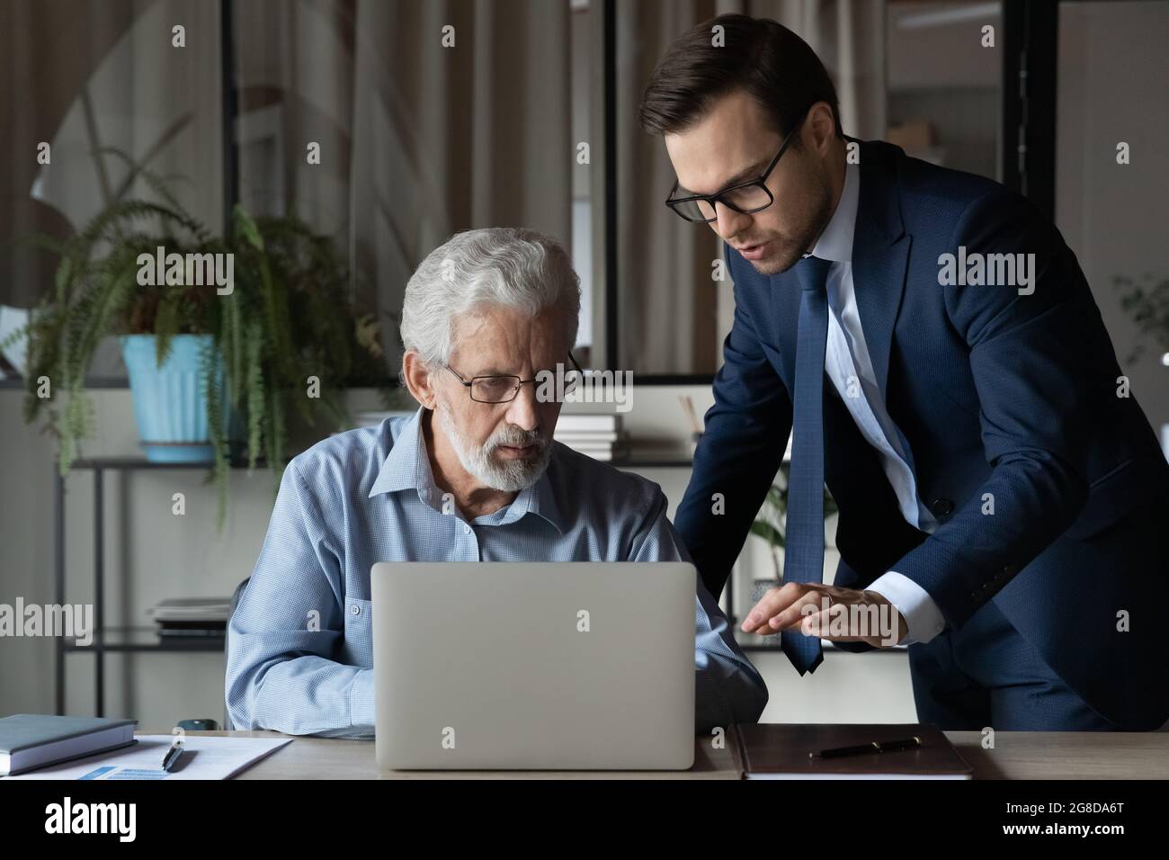 Senior Boss berät jungen Experten über Computerprobleme Stockfoto