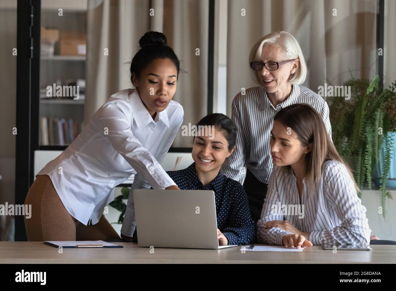Multiethnisches, vielfältiges Geschäftsteam aus weiblichen Mitarbeitern, das sich am Laptop trifft Stockfoto