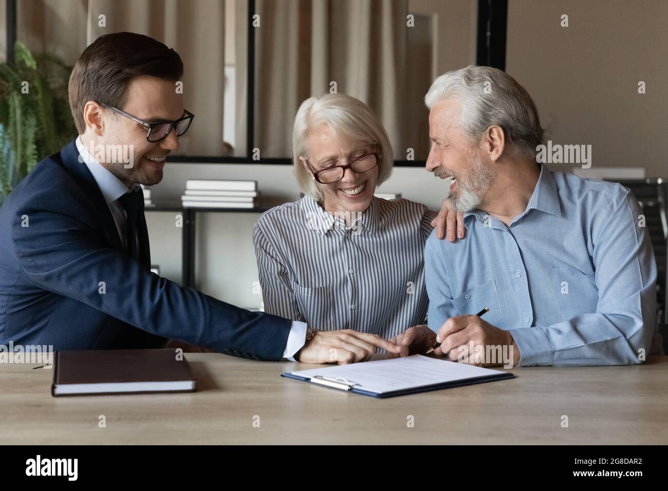 Glückliches Seniorenpaar, das eine Krankenversicherung unterzeichnet Stockfoto
