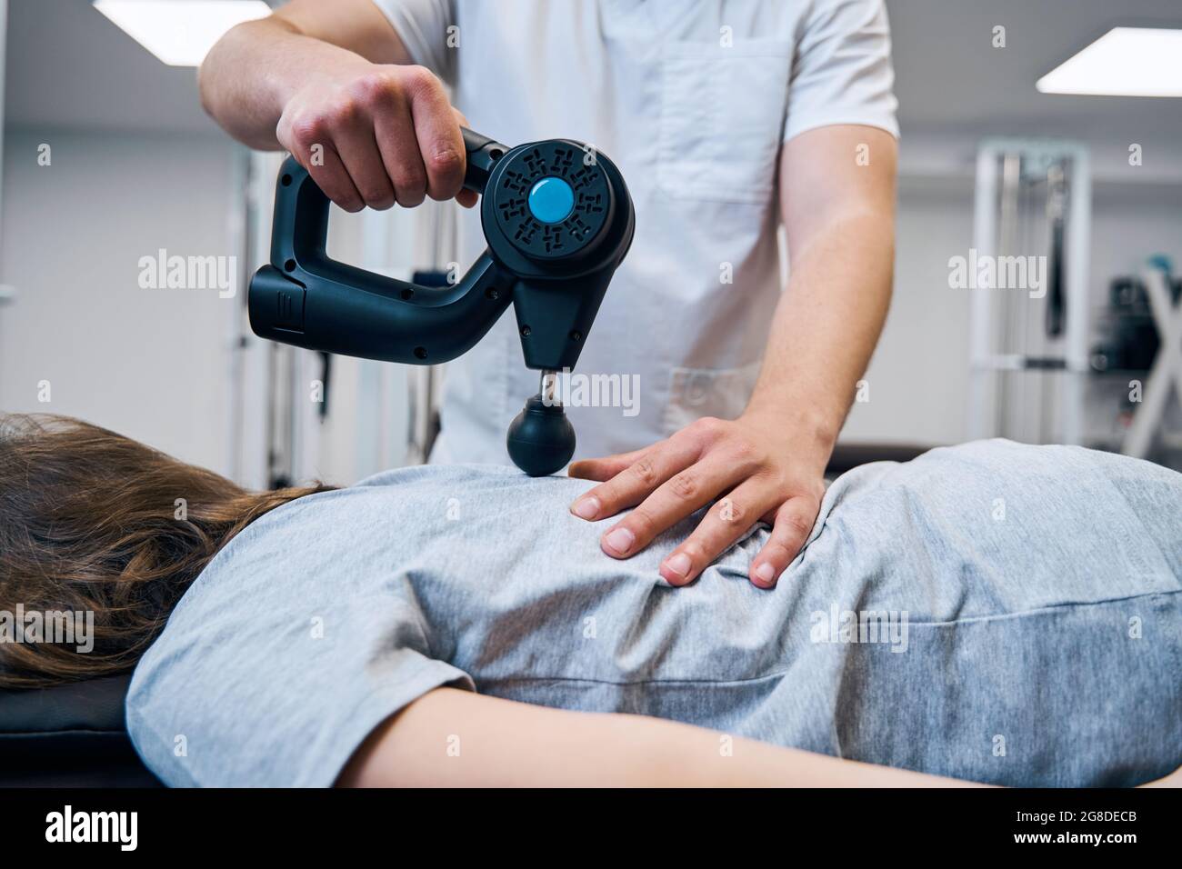 Masseur mit Massagegerät Perkussionspistole behandelt Mädchen Rücken und  Wirbelsäule während der Therapiestunde Stockfotografie - Alamy