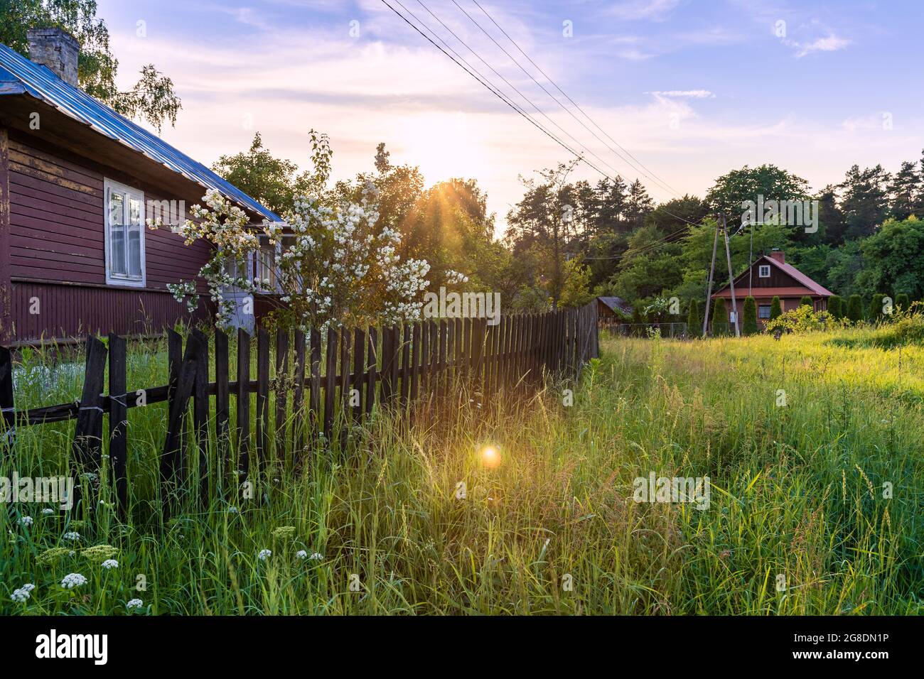 Schönes, traditionelles, polnisches Dorf bei Sonnenuntergang. Alte, hölzerne Gebäude neben grüner, frischer Wiese. Idyllischer Blick auf die Landschaft. Krasnobród, Roztocz Stockfoto
