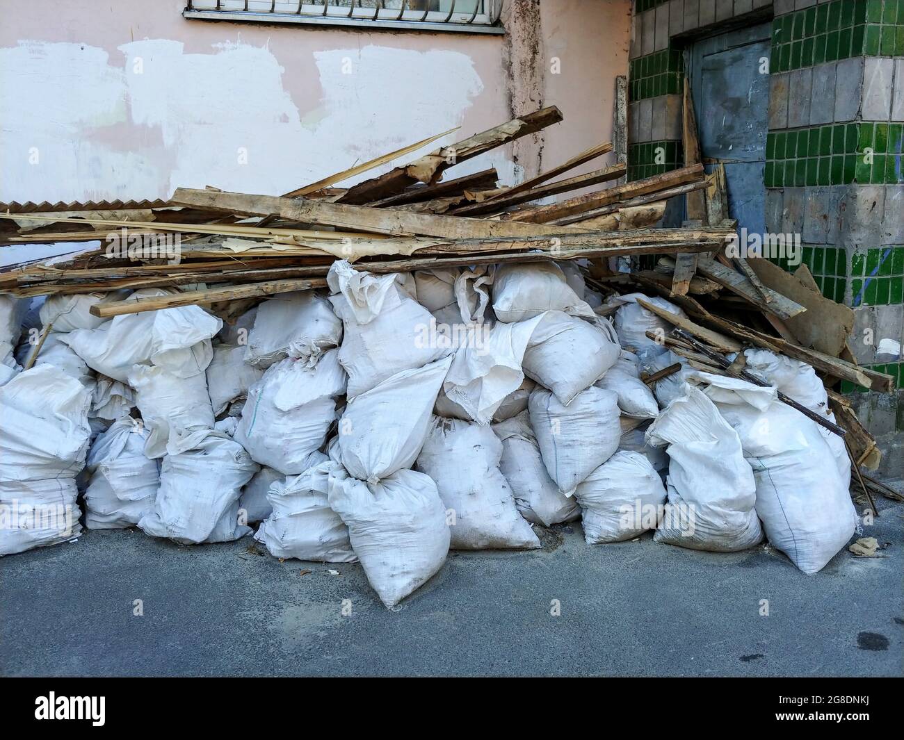 Haufen weißer Säcke mit Baumüll und Holzbohlen. Baumüll nach Hausreparatur Renovierung hinterlassen Stockfoto