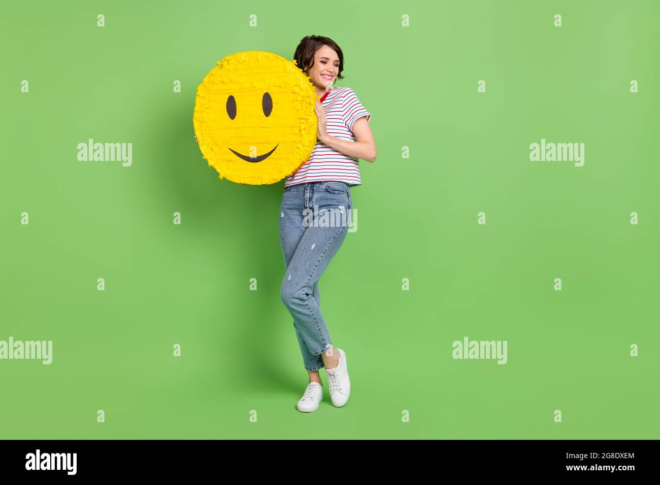 In voller Länge Körpergröße Ansicht der attraktiven fröhlichen Mädchen umarmt großen Emoji isoliert über grüne Pastellfarbe Hintergrund Stockfoto